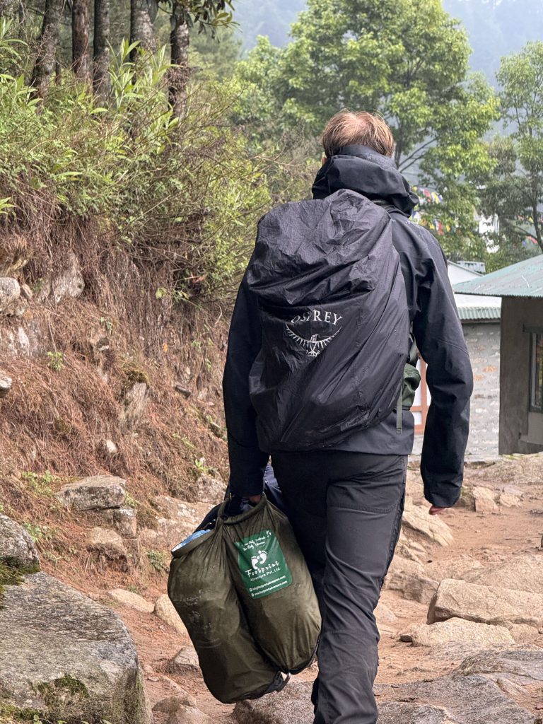 Volunteer carrying a clean-up bag down the trail