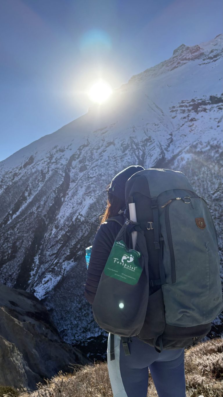 Trekker with a Footprint clean-up bag at sunrise